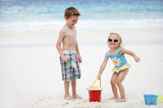 Boy and girl playing in the sand on the beach, La Digue, Indian Ocean, Seychelles, Africa