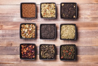 Various tea in a black ceramic bowls on a wooden table