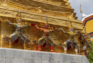 A picture of statues at the base of a golden chedi at the Grand Palace, in Bangkok