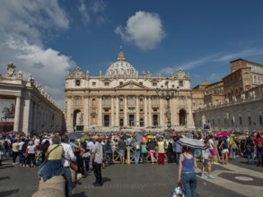 St Peter's Basilica with a large crowd in the square in front of it under a clear blue sky, rome,