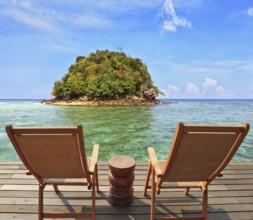 The charming landscape. A green island in a sea bay with emerald water. Two wooden chairs - on a