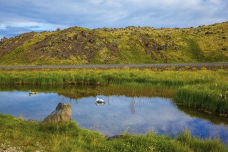 Small lake with thermal water. In the smooth surface of the water reflects the sky and clouds.