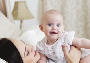 Happy smiling mother with six month old baby girl indoor