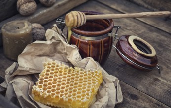 Honeycomb wrapped in grey paper on the background of the jars