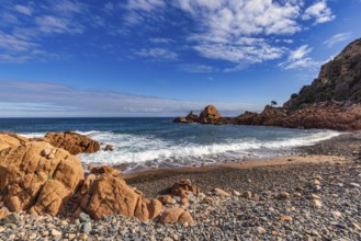 Coastal landscape with red rocks and surf in blue sky and sunshine, Spiaggia di Cala E'Luas,