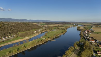 River (Danube) running through the landscape with neighbouring meadows and hills, under a blue sky,