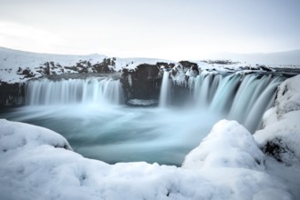A majestic waterfall surrounded by snow and ice in a wintry landscape, Iceland, Godafoss, Europe