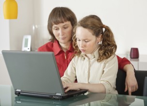 Mother and teenager girl with laptop computer together at home, Belgium, Europe