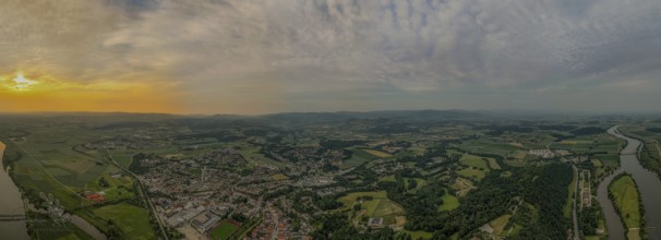 Aerial view of a cityscape with river, fields and forests at sunset under a cloudy sky, Bogen,