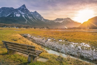 Charming winter scenery with a wooden bench on the side of a small river with a view towards the