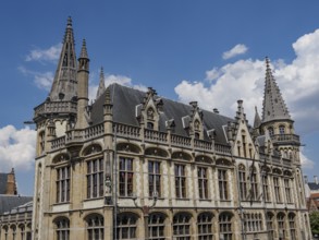 Majestic building with pewter towers and detailed decorations on a clear blue sky, Ghent, Belgium,
