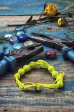 Beads, pliers, and other needlework accessories on outdated turquoise wooden background