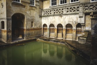 Water and buildings in an old roman bath in the city of Bath in the united kingdom england