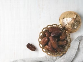 Metal plate of sweet dried dates and linen cloth on gray cement background. Dried dates with copy