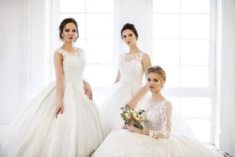 Three young woman with bouquets wearing wedding dresses