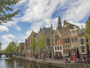 View of a canal with historic buildings and a church under a partly cloudy sky, Amsterdam,
