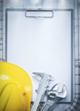 Clipboard building helmet adjustable spanner vernier caliper on blueprint construction concept