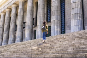 Confident mid-adult student walking up university steps
