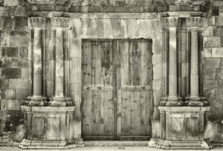 Monochrome sepia ancient wooden double doors in an old stone building with crumbling ornate columns
