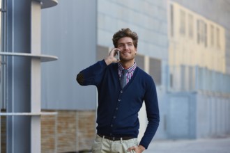Young businessman talking smartphone phone walking on the street