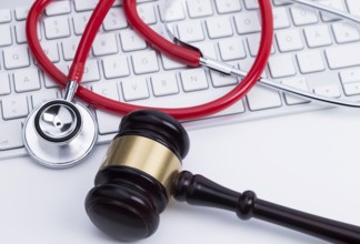 Photo shows an auction hammer and a stethoscope on a computer keyboard
