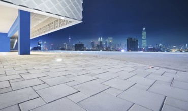 Perspective view of empty floor with modern building exterior and cityscape skyline . Night scene