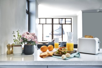 White electric bread toaster with orange juice with sandwich on kitchen table. Breakfast in the