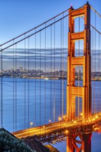 Detail of the famous Golden Gate Bridge at dawn with the San Francisco skyline in the background