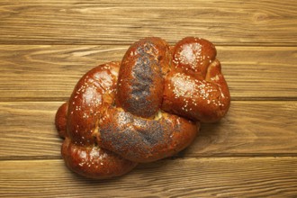 Freshly baked Challah bread covered with poppy and sesame seeds, top view on rustic wooden