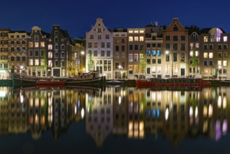 Reflection of the buildings along the canal at night in Amsterdam, Netherlands