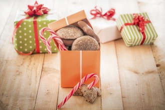 Orange colored gift box full of sweets, gingerbread and candies, on a wooden table