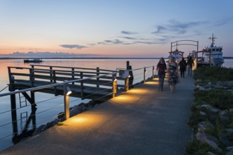 Boardwalk and ferry at the calm Baltic Sea in scenic evening light