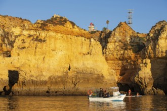 Stand-up paddler and fishing boat at Ponta de Piedade, Lagos, Algarve, Portugal, Europe