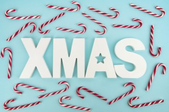 Zuckerstangen und hölzerne XMAS-Buchstaben auf blauem, hellem Hintergrund