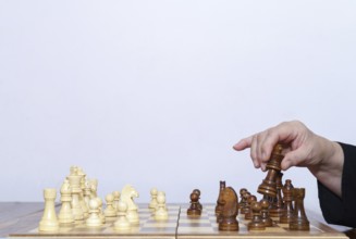 Close-up of a woman's hands playing chess with a white background and copy space