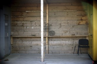 A wooden alcove between two construction trailers is used as a barbecue area
