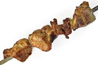 Slices of fried meat and onions on a skewer isolated on a white background