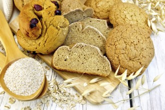 Bread, rolls and biscuits oat, bran in a spoonful, oat stalks on a background of wooden boards