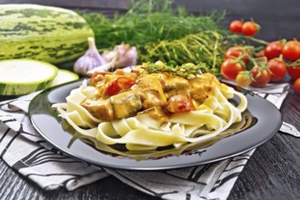 Tagliatelle pasta with meat goulash, tomato, zucchini and thyme in a plate on napkin, garlic, spicy