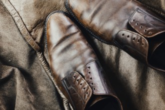 Close-up of brown leather shoes on a leather jacket, contributing to a rustic atmosphere