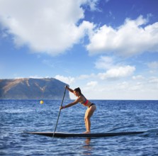 SUP Stand up Surf girl with paddle in a blue ocean sea