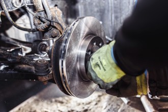 Mechanic adjusting a brake system part, focused on hands in a workshop
