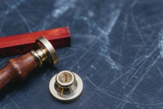 Brass seal with red wax on a textured dark background