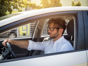 Handsome man sitting in his car, looking straight ahead and driving