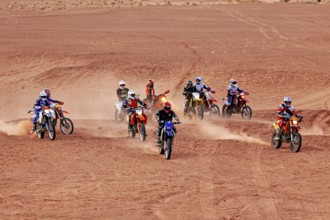 Several motorcyclists on the move, stirring up sand while driving in the desert, By off road