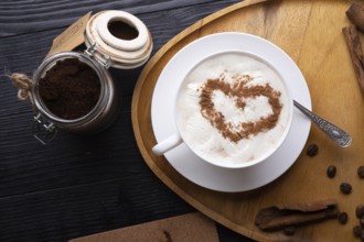 Porcelain cup of coffee with ice cream and cinnamon heart served at black wooden table. life style