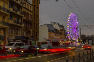 Traffic in Old Town with House and Building and Illuminated Ferris Wheel in a Cloudy Night in