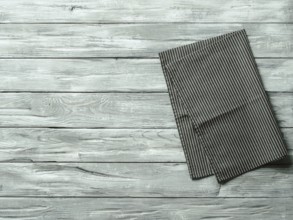 Gray wooden table with balck and white dark linen kitchen towel or textile napkin flat lay. Dark