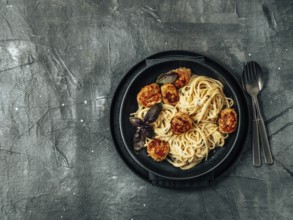 Zucchini Parmesan Meatballs with Pasta Carbonara in black craft plate over gray background. Close