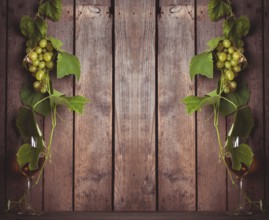 Grapes with leaves and glass of wine on the wood background